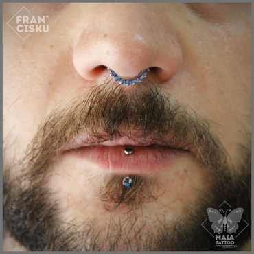 Fotografia di un viso di uomo, con piercing al setto, con gioiello a clicker e opali Teal di Industrial Strength , eseguito da Francesco Deschino presso lo studio Maia tattoo di Milano Cornaredo