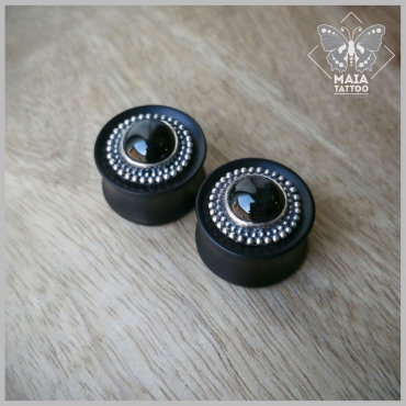 Fotografia di due plugs in legno di ebano con inserti in argento e pietra Diopside nera, realizzati a mano da Mysteeco Unique Body Jewellery, disponibili presso il Maia Tattoo di Milano Cornaredo