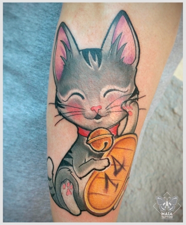 Fotografia di un avambraccio maschile con un tatuaggio di un maneki neko, anche noto come 
