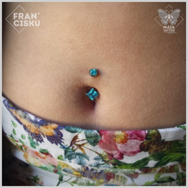 Fotografia di un piercing all'ombelico con gioiello Industrial Strength con pietre colore mint green e taglio square princess, eseguito da Francesco Deschino al Maia Tattoo di Milano Cornaredo