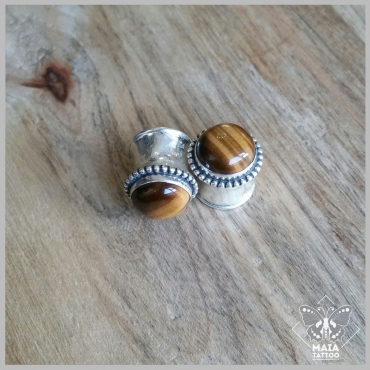Fotografia di due Dilatazioni double flair in argento con inserimento di pietra tiger eye, realizzati a mano da Meesteco, disponibili presso Maia Tattoo Milano Cornaredo